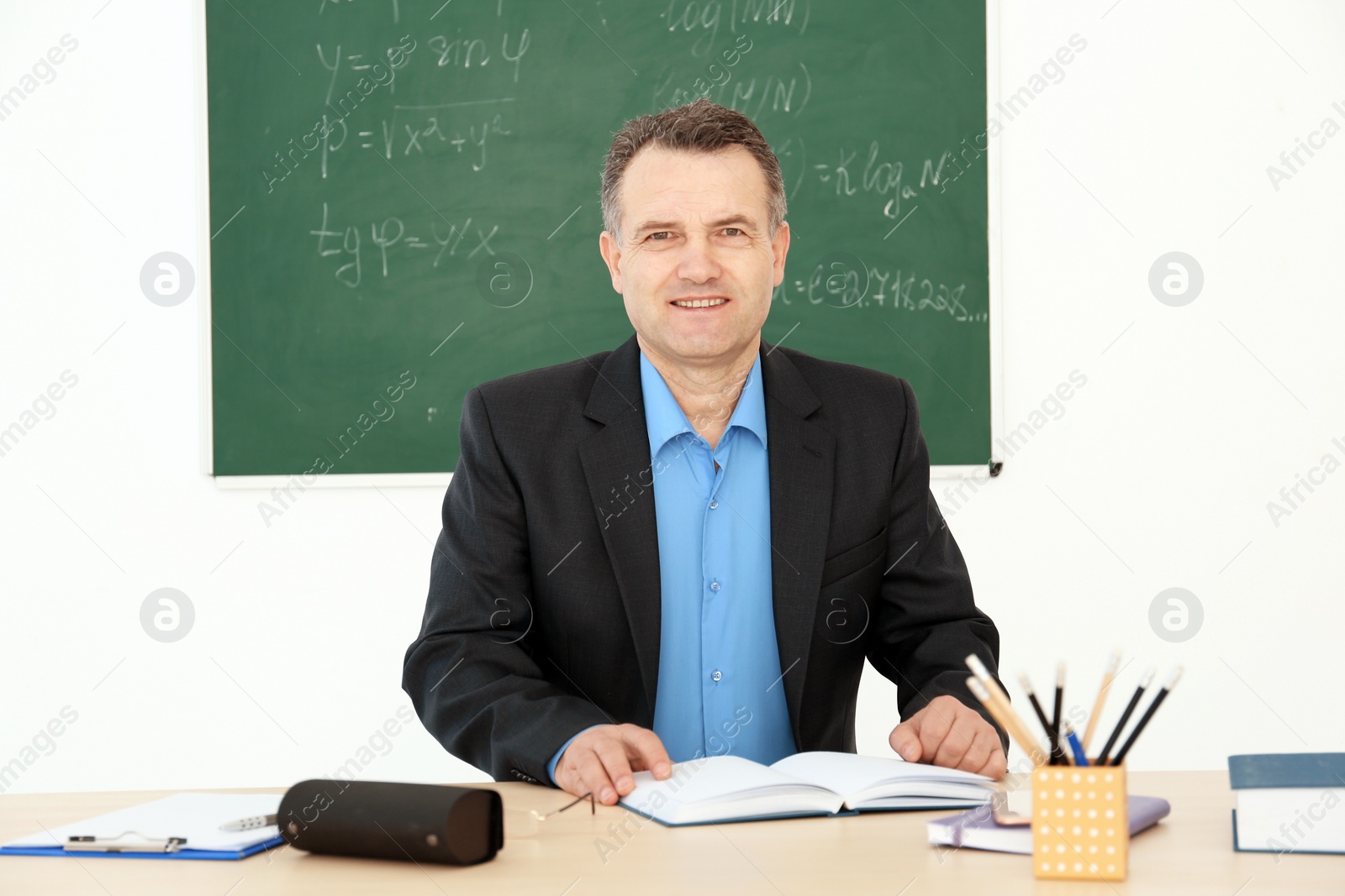 Photo of Male teacher working at table in classroom