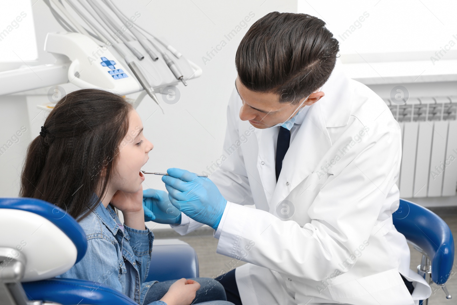 Photo of Professional dentist working with little girl in clinic