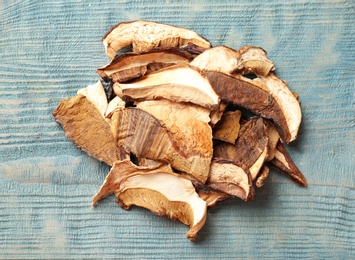 Photo of Delicious dried mushrooms on color wooden background, top view