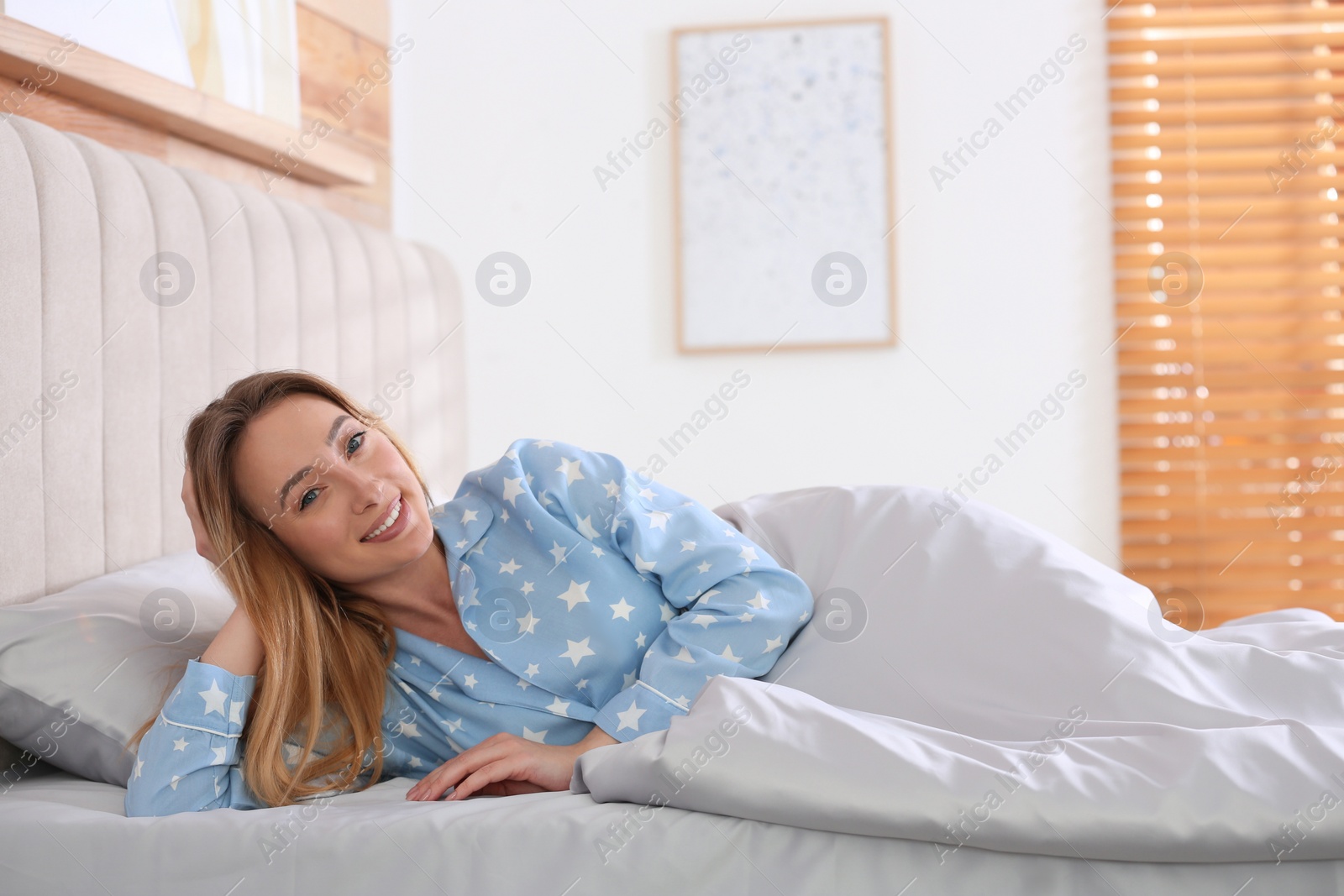 Photo of Young woman lying in comfortable bed with silky linens