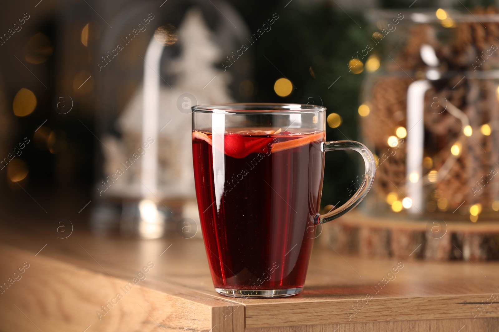 Photo of Delicious mulled wine in glass cup on wooden table, closeup