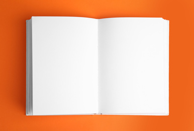 Photo of Open book with blank pages on orange background