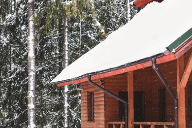 Wooden cottage with snowy roof. Winter vacation