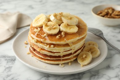 Photo of Delicious pancakes with bananas, walnuts and honey on white marble table, closeup