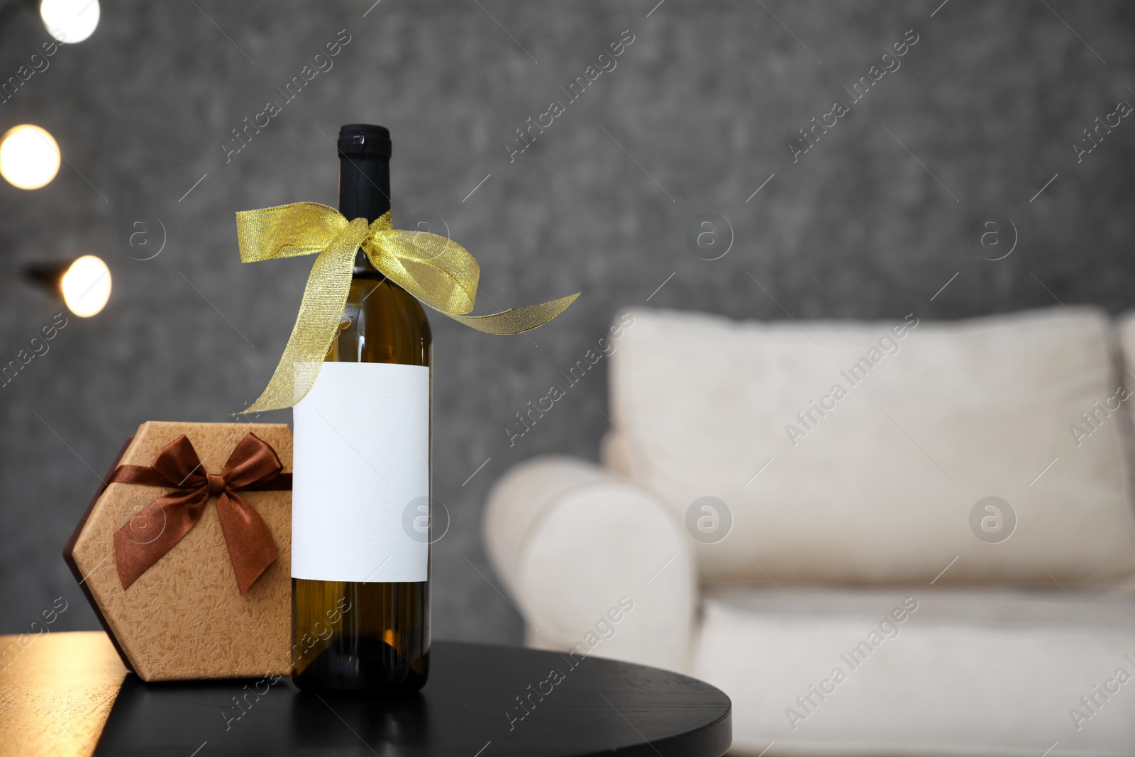 Photo of Gift box and bottle of wine on table in room. Space for design