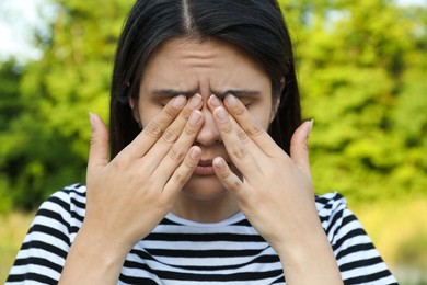 Photo of Young woman suffering from eyestrain outdoors on sunny day