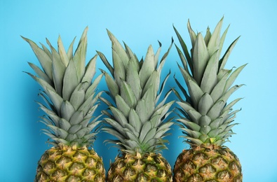 Photo of Ripe juicy pineapples on light blue background