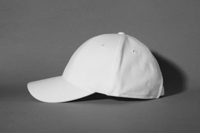 Stylish white baseball cap on grey background