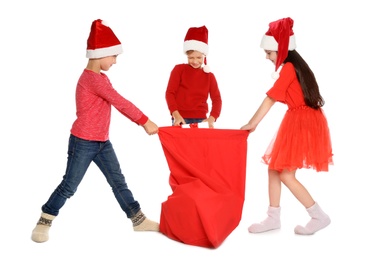 Photo of Cute little children in Santa hats with red Christmas bag on white background