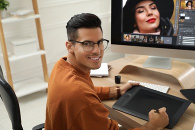 Photo of Professional retoucher working with graphic tablet at desk in office