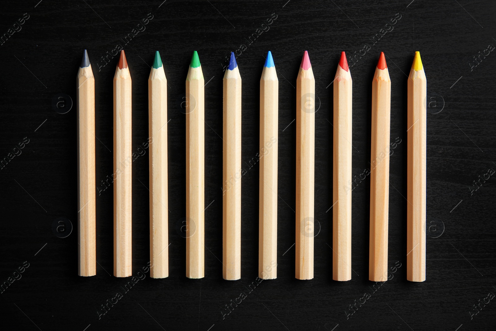 Photo of Pencils of different colors on wooden background, top view. School stationery