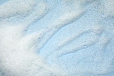 Photo of White washing foam on color background, top view