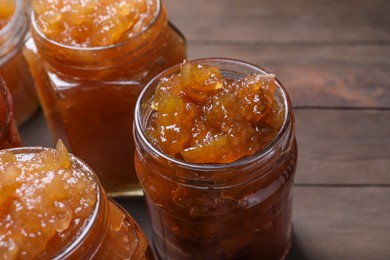 Photo of Delicious apple jam in jars on wooden table, closeup