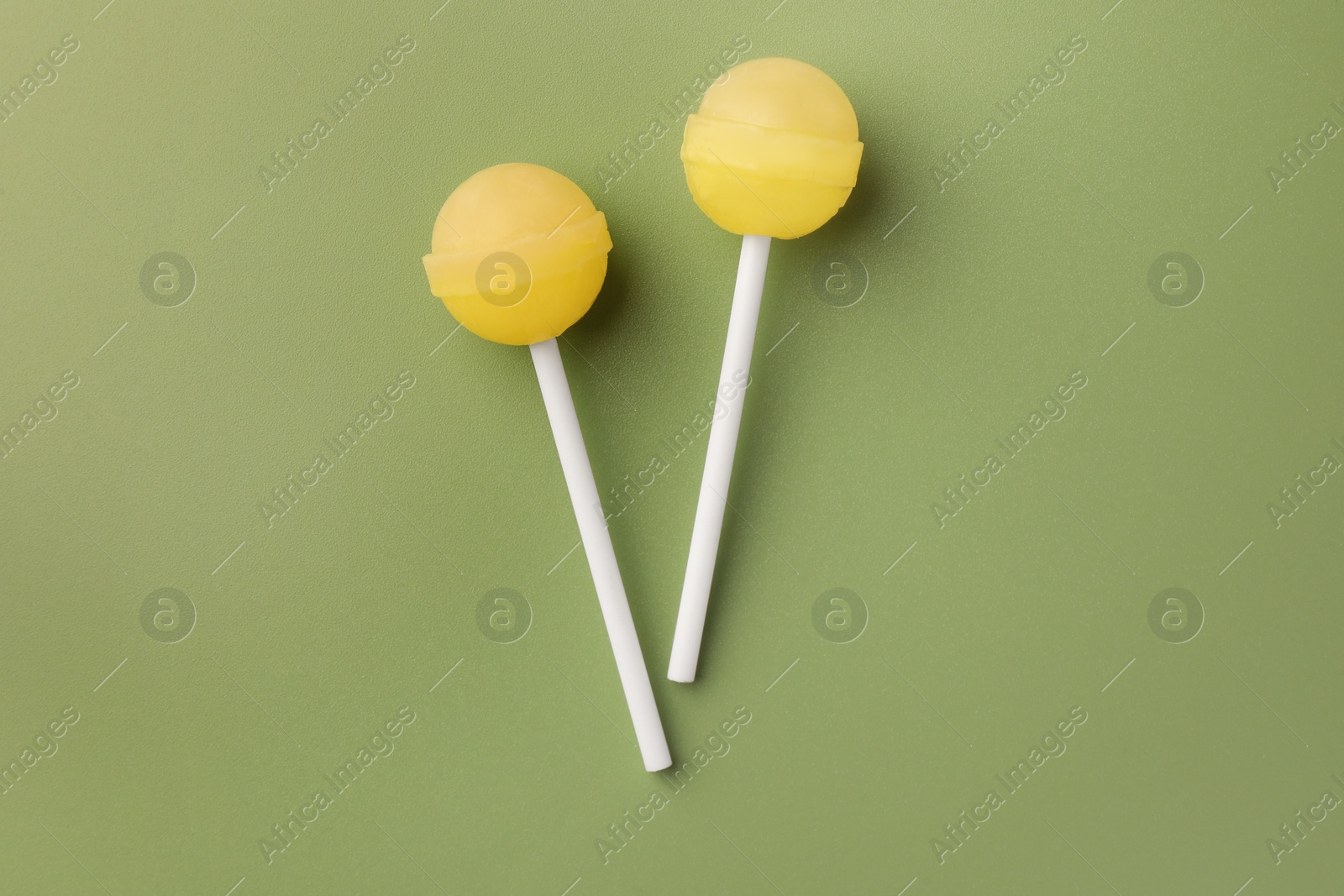 Photo of Tasty lollipops on green background, flat lay