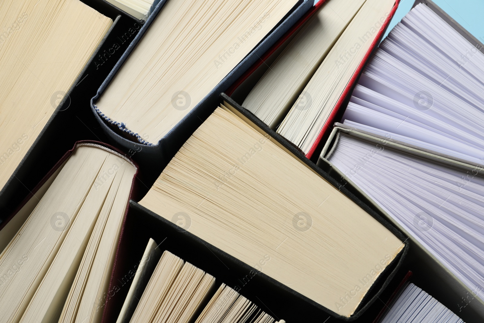 Photo of Many hardcover books on light blue background, closeup