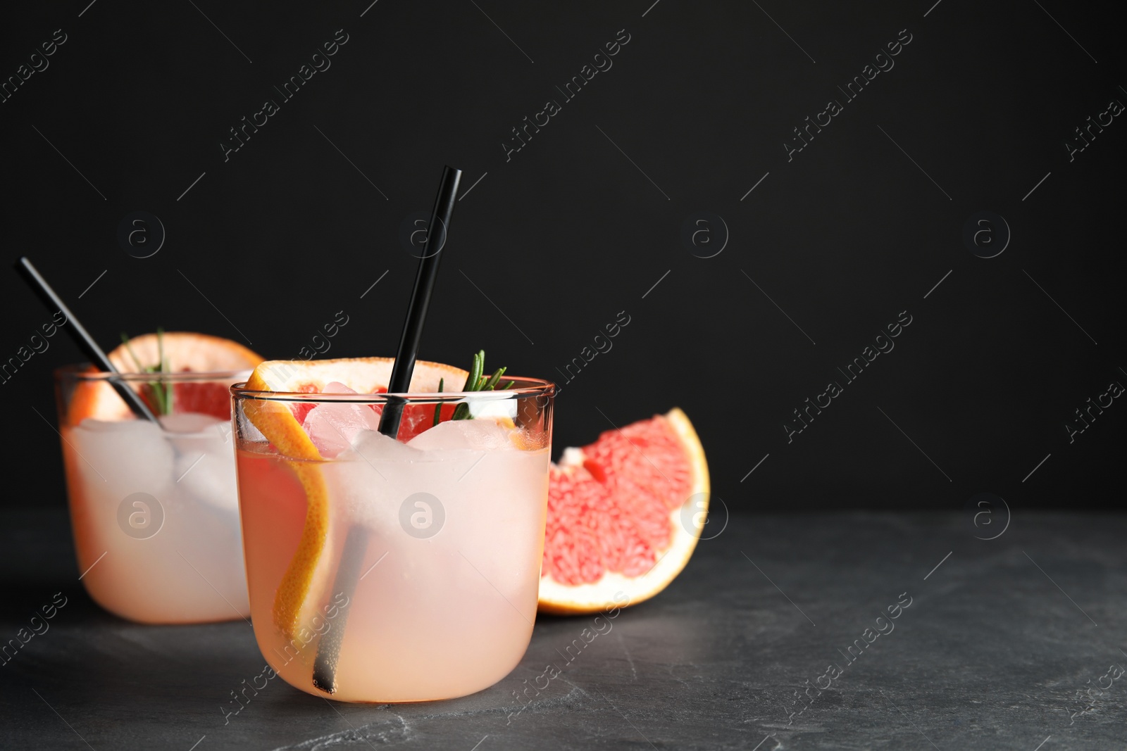 Photo of Glasses of cocktail and grapefruit slice on table. Space for text