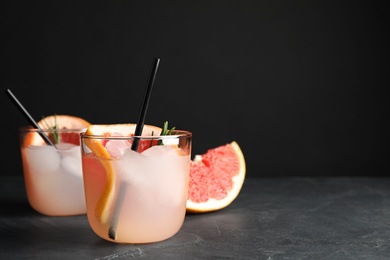 Photo of Glasses of cocktail and grapefruit slice on table. Space for text