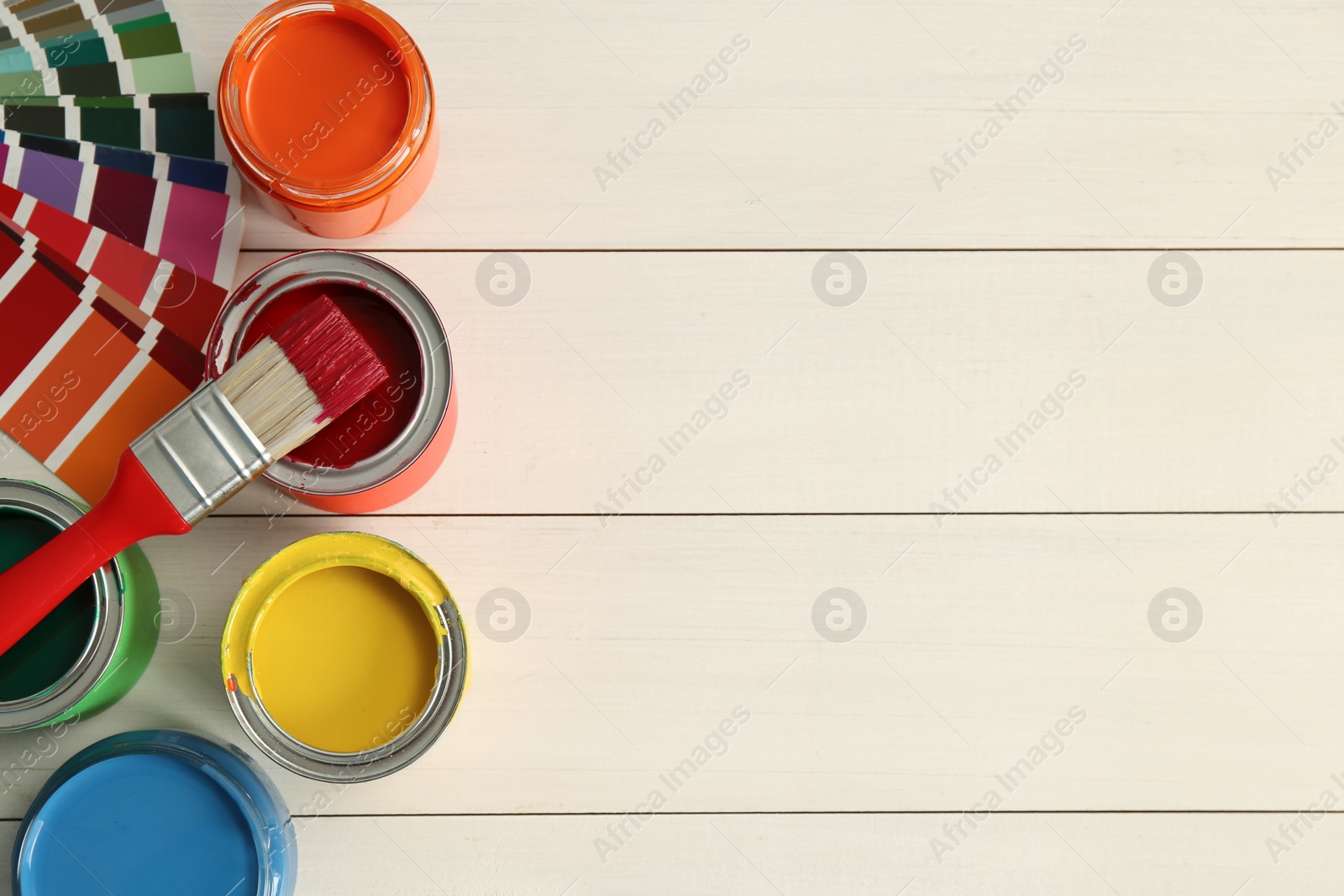 Photo of Different paints, brush and palette on white wooden background, flat lay. Space for text