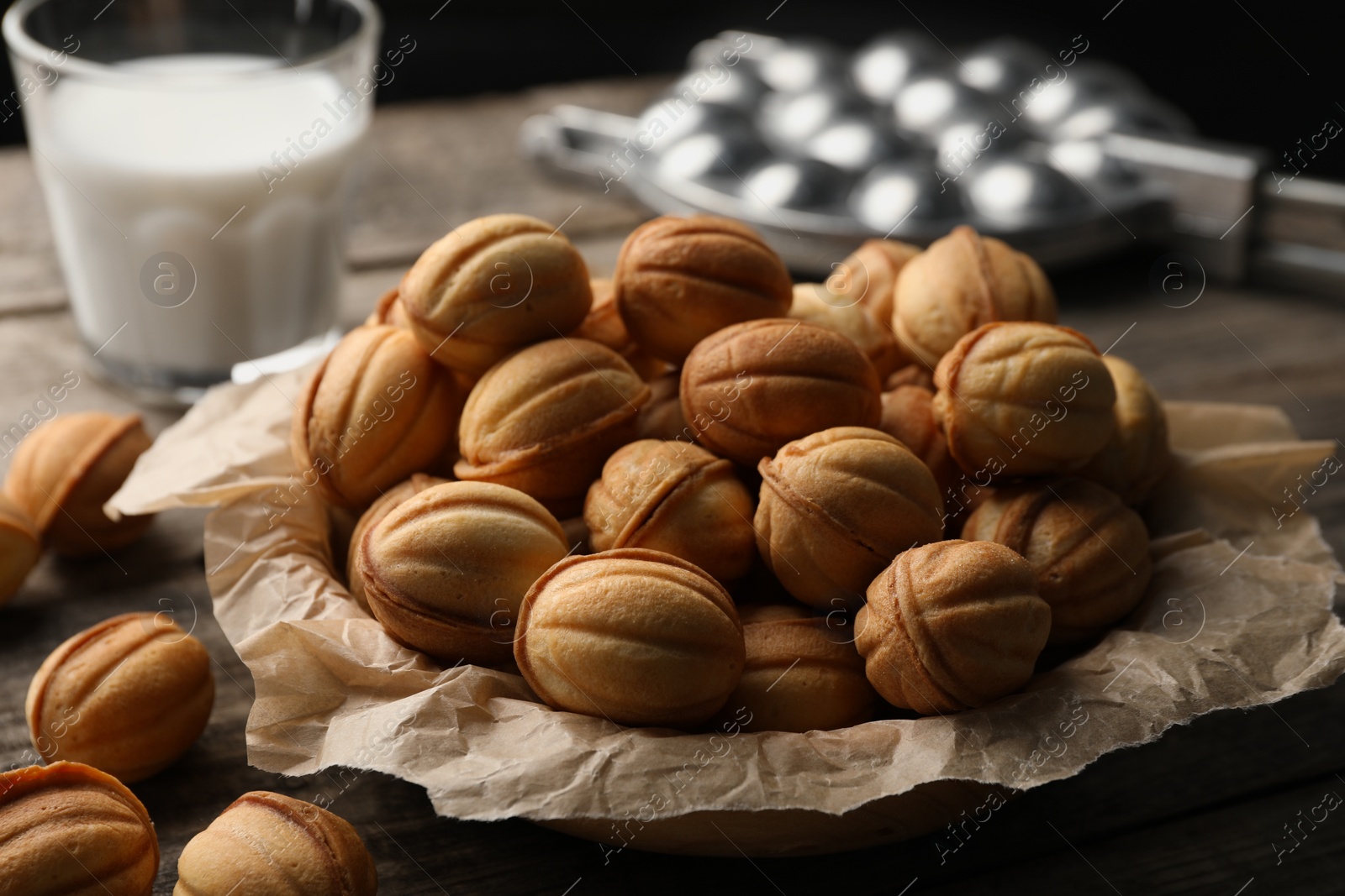 Photo of Bowl of delicious nut shaped cookies on wooden table, closeup