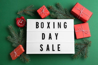 Lightbox with phrase BOXING DAY SALE and Christmas decorations on green background, flat lay