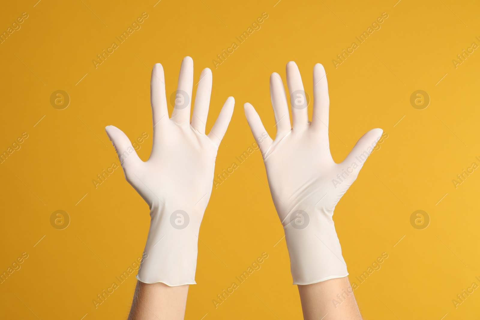 Photo of Doctor wearing medical gloves on yellow background, closeup