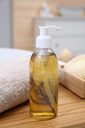 Photo of Dispenser of liquid soap, fresh towel and loofah on wooden surface in bathroom