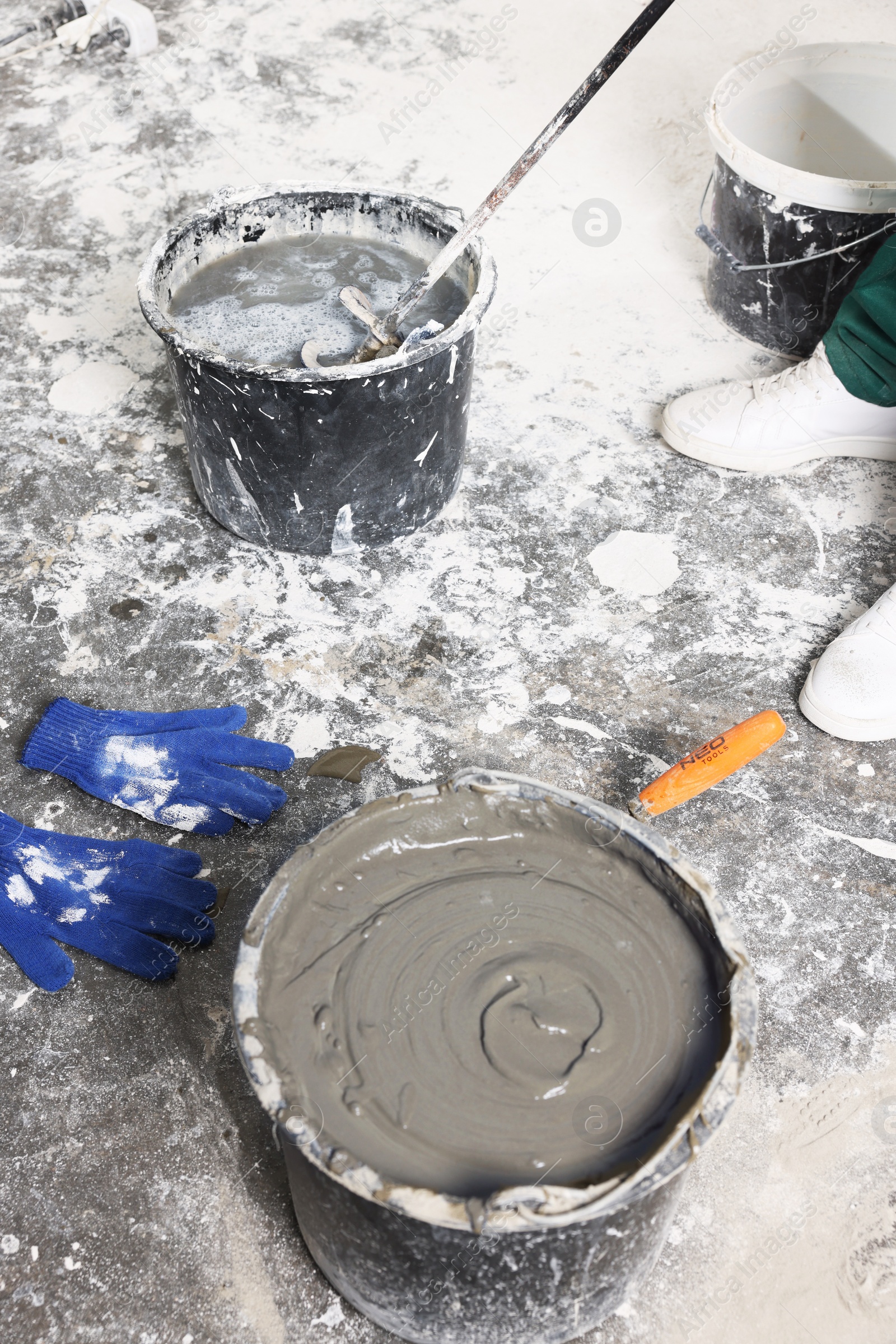 Photo of Worker mixing concrete in bucket indoors, closeup