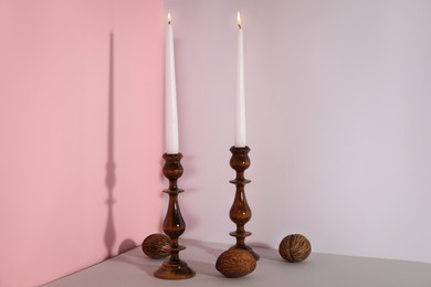 Elegant candlesticks with burning candles on light  table