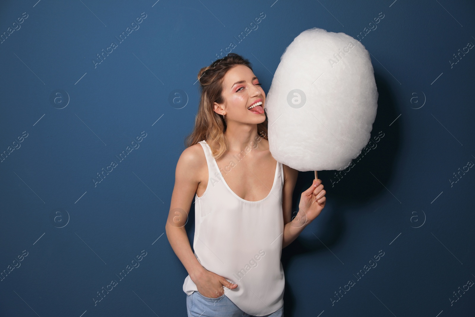 Photo of Portrait of pretty young woman with cotton candy on blue background