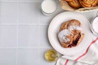 Photo of Delicious rolls with sugar powder and berries on white tiled table, flat lay with space for text. Sweet buns