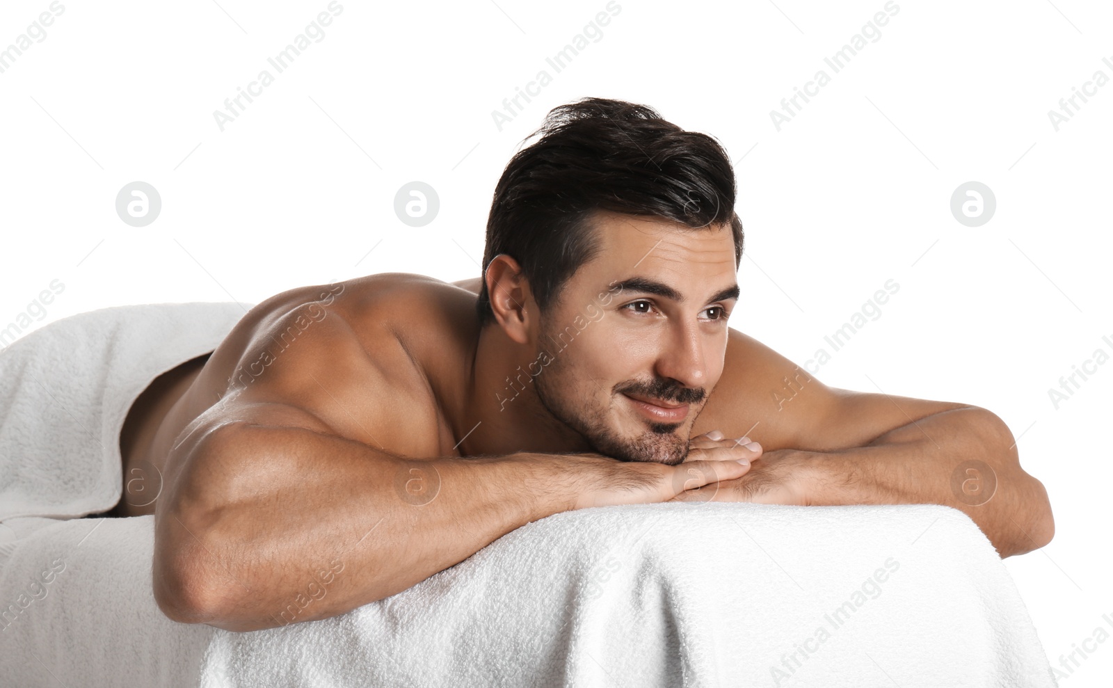 Photo of Handsome young man relaxing on massage table against white background. Spa salon
