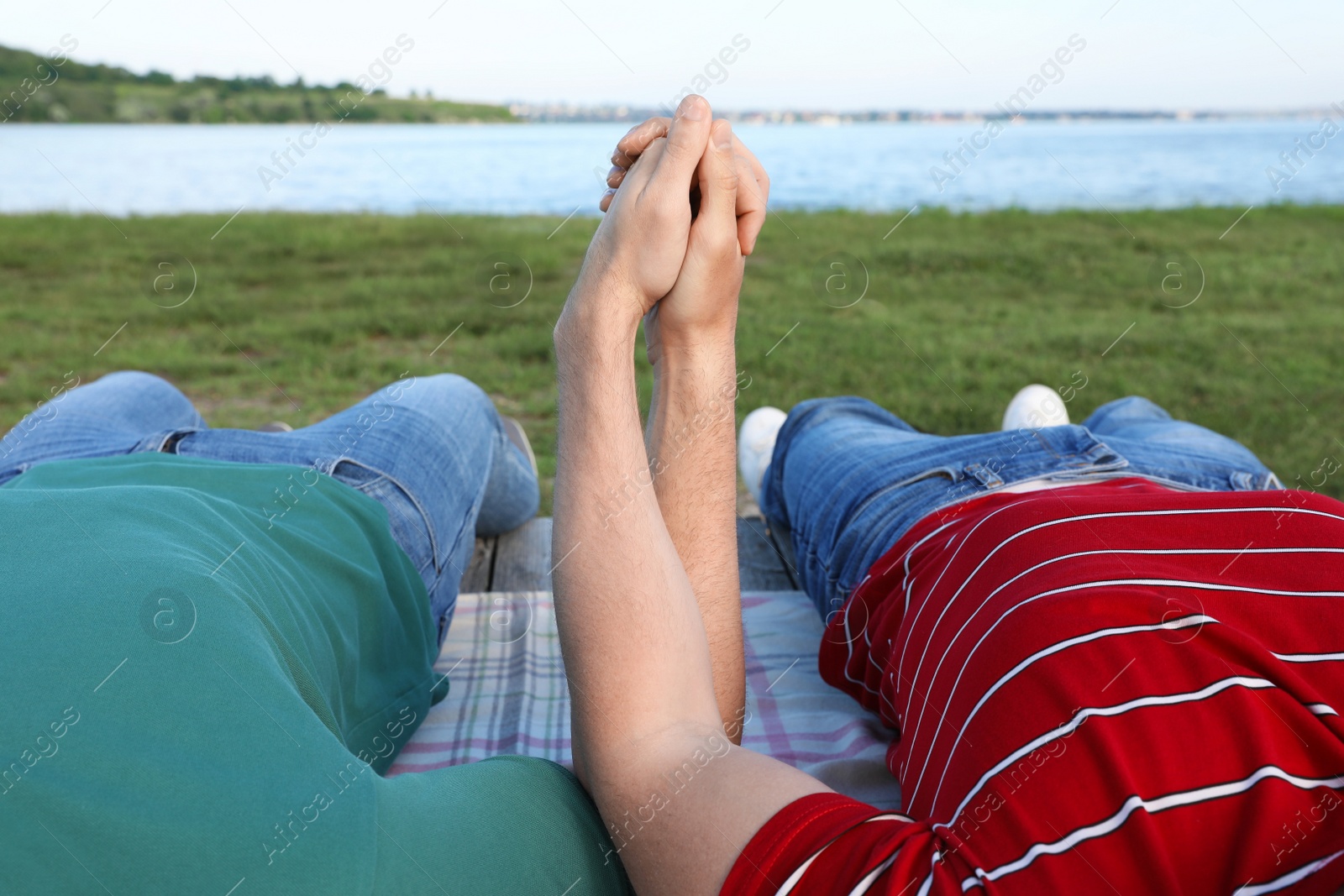 Photo of Gay couple lying near river on sunny day, closeup