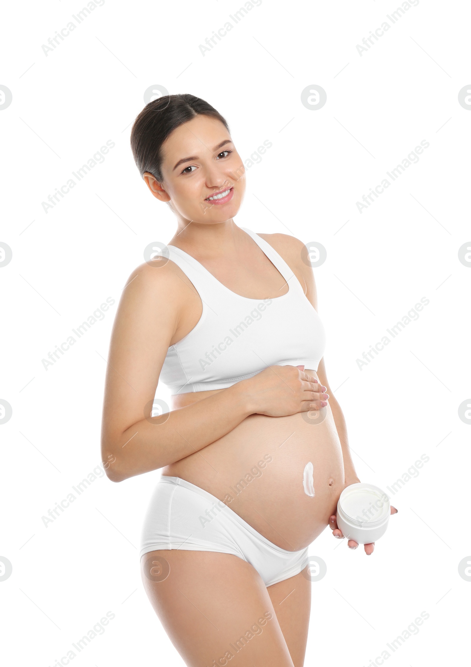 Photo of Pregnant woman applying body cream on belly against white background