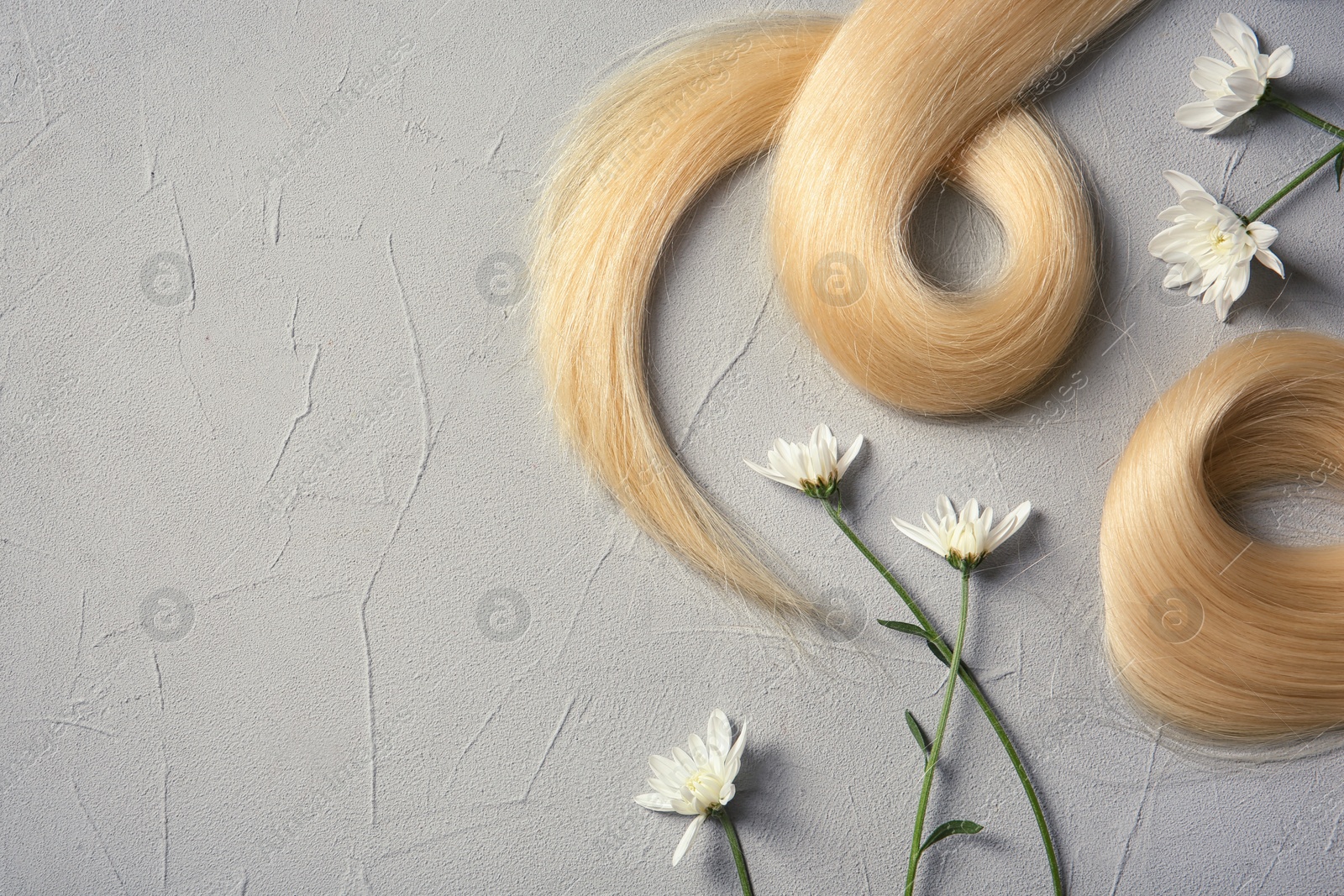 Photo of Composition with locks of blond hair and flowers on color background, flat lay. Space for text