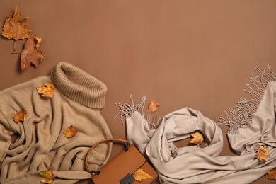Photo of Flat lay composition with sweater and dry leaves on brown background, space for text. Autumn season