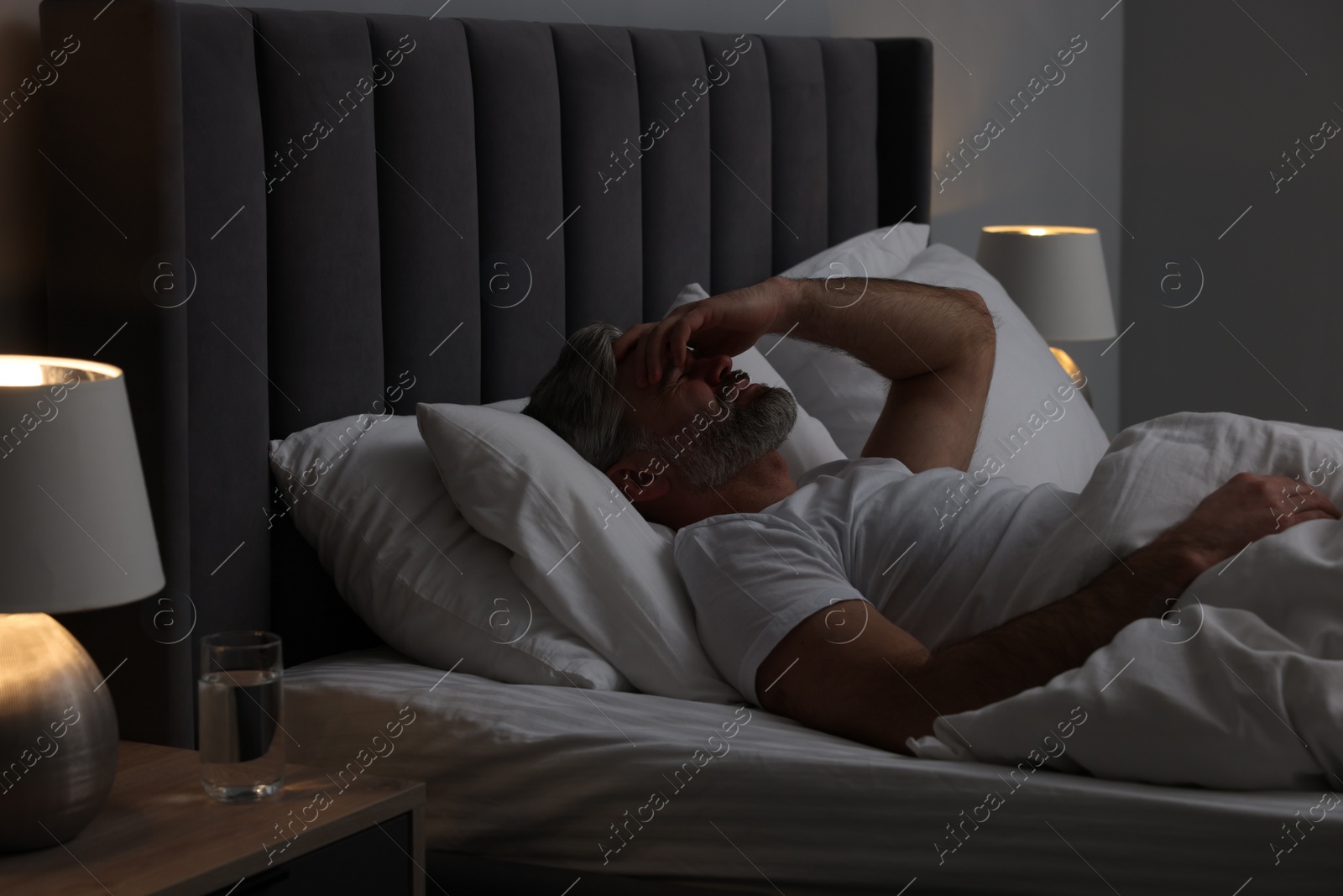Photo of Mature man suffering from headache in bed at night