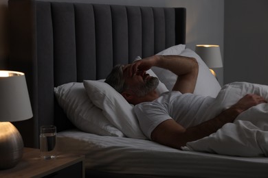 Mature man suffering from headache in bed at night