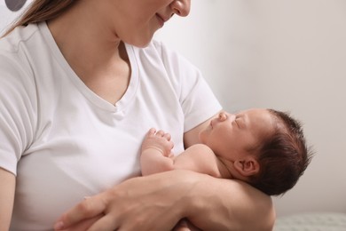 Mother holding her cute newborn baby indoors, closeup