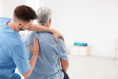 Photo of Young physiotherapist working with senior patient in clinic