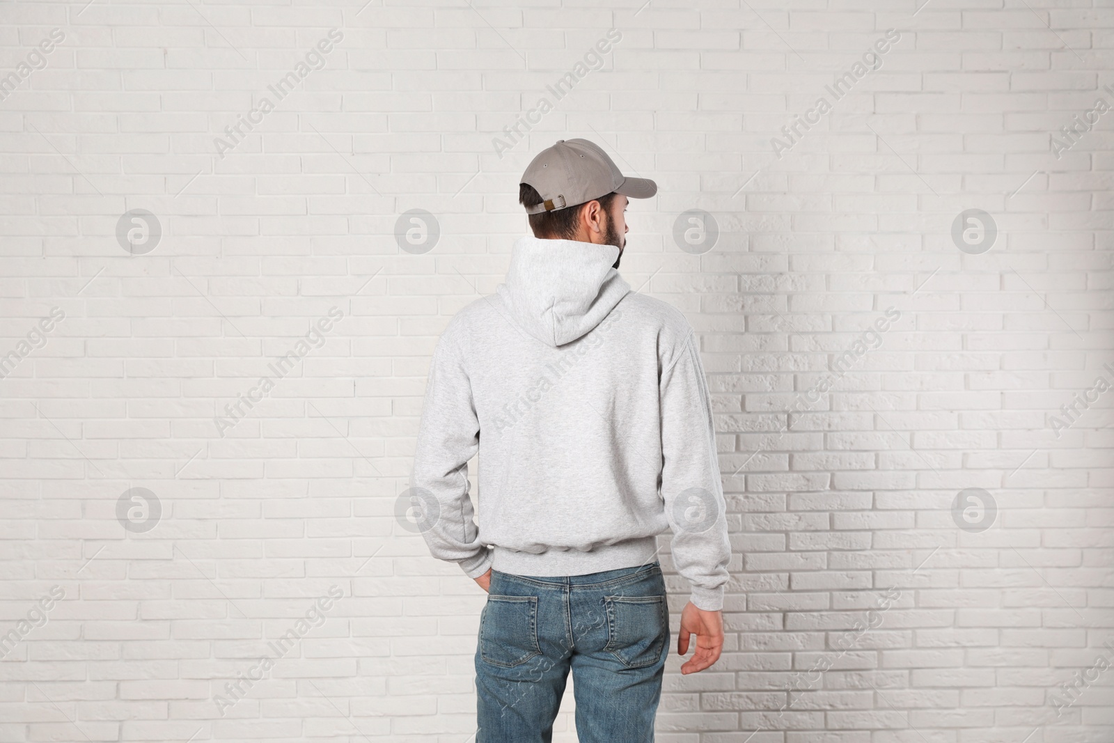 Photo of Young man in sweater at brick wall. Mock up for design