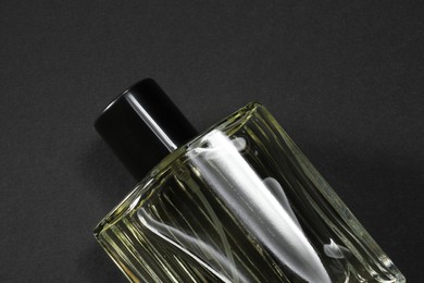 Luxury men`s perfume in bottle on black background, top view