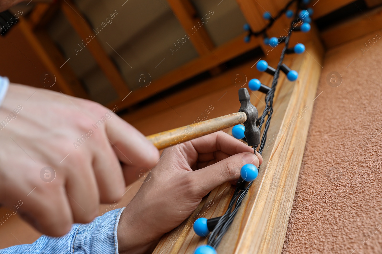 Photo of Man decorating house with Christmas lights outdoors, closeup