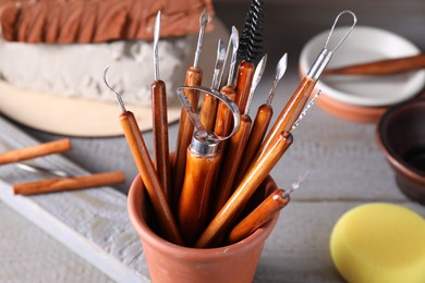 Clay and set of crafting tools on grey wooden table in workshop, closeup