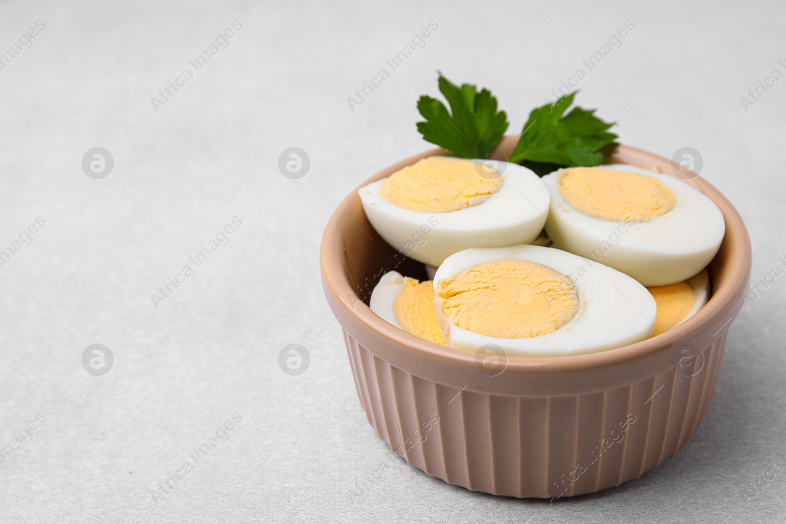 Photo of Fresh hard boiled eggs and parsley on light grey table. Space for text