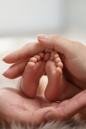 Photo of Mother and father holding their newborn baby, closeup view on feet. Lovely family