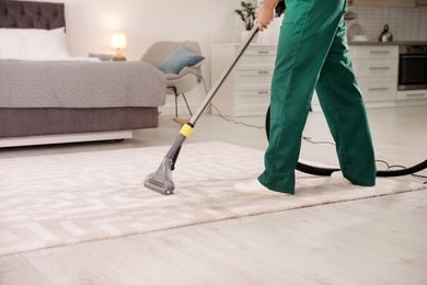 Photo of Professional janitor cleaning carpet in house, closeup