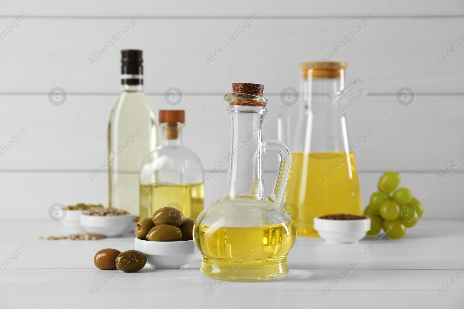 Photo of Vegetable fats. Different cooking oils in bottles and ingredients on white wooden table