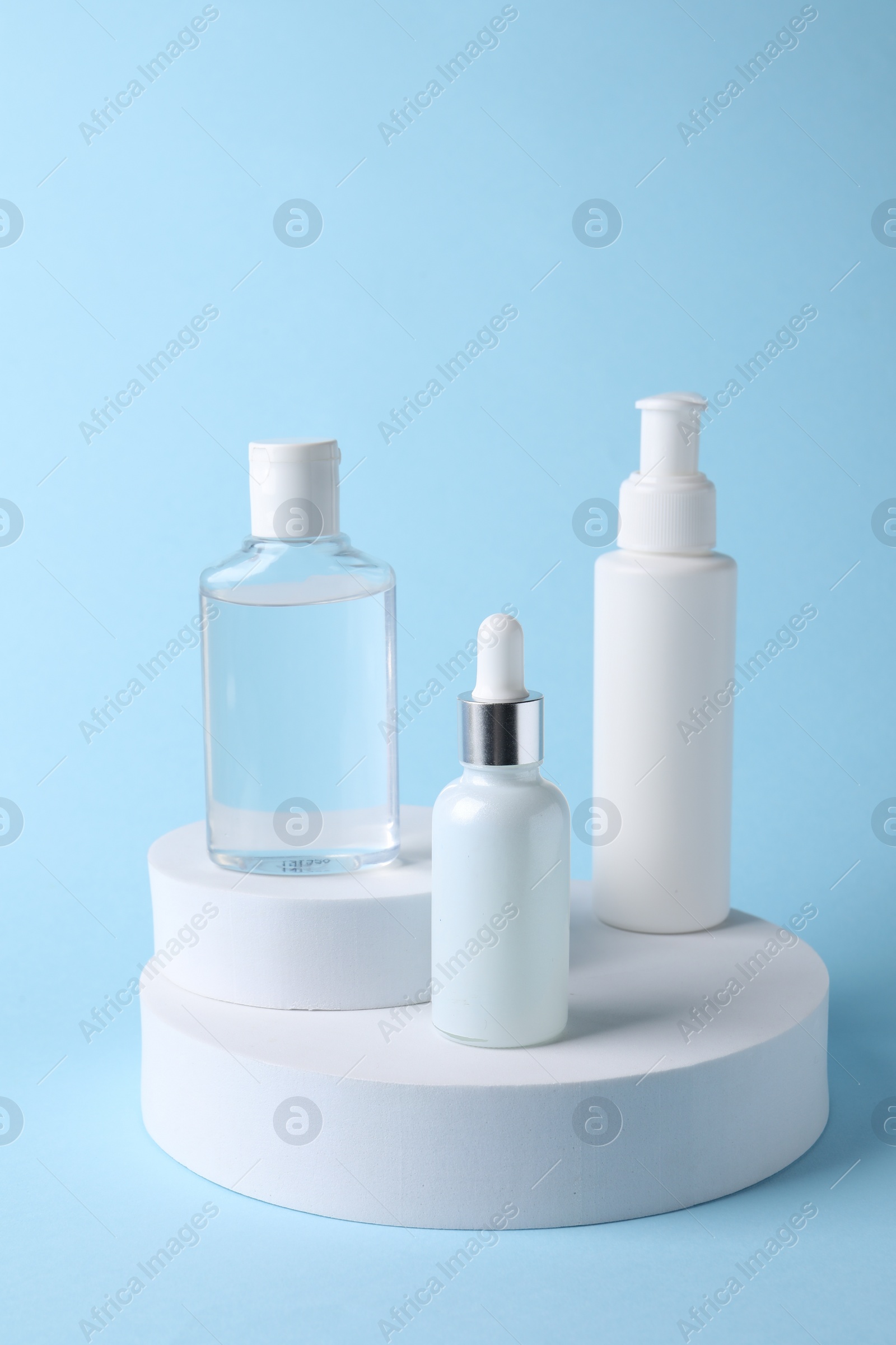 Photo of Presentation of bottles with cosmetic serums on light blue background