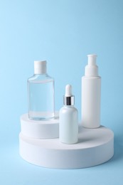 Presentation of bottles with cosmetic serums on light blue background