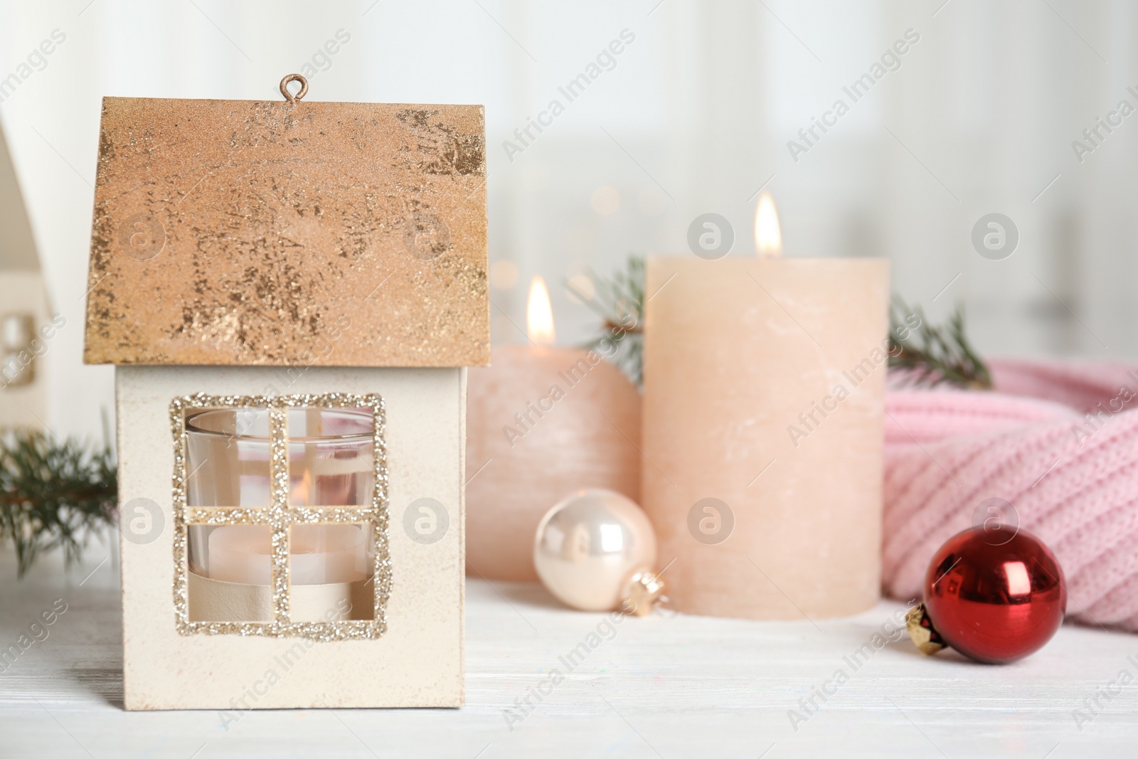 Photo of Composition with candle in house shaped holder on white wooden table. Christmas decoration